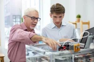 Älterer Mann unterstützt einen jungen Mann bei der Assistierten Ausbildung (AsA).