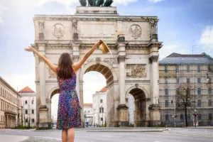 Frau vor Siegestor in München freut sich über den Ferienpass München 2024